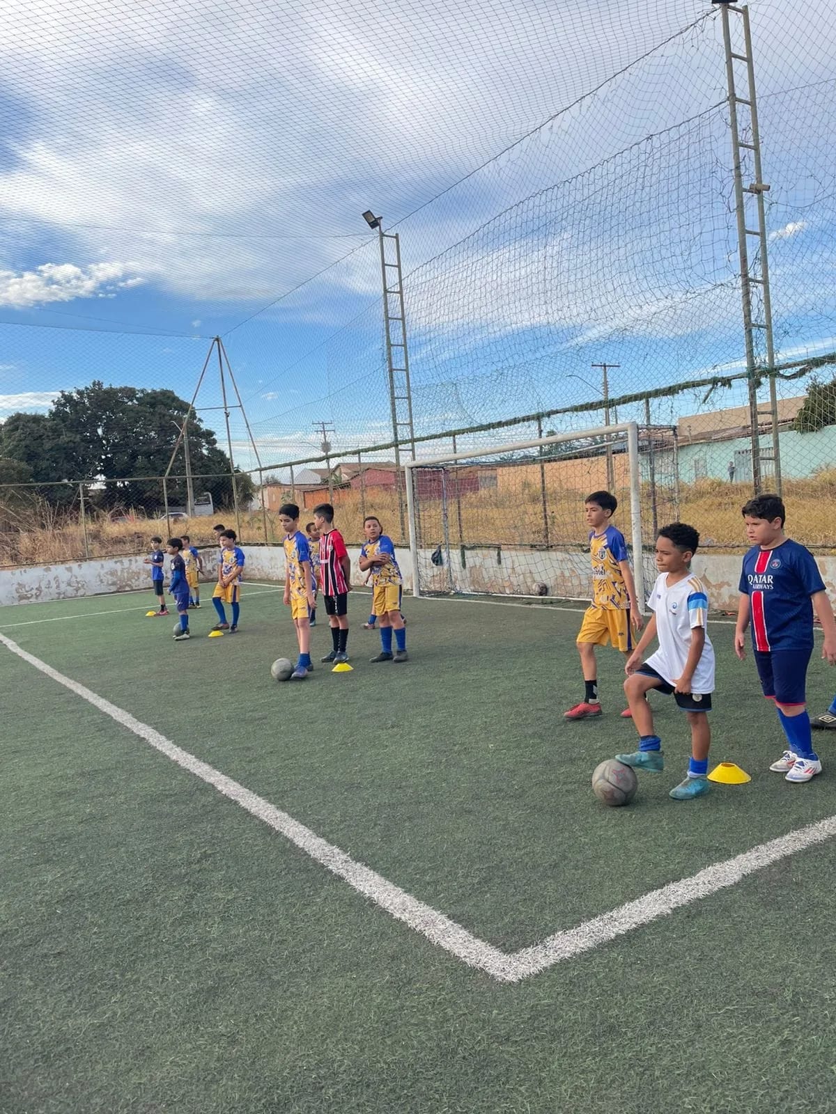 Treino com cones em campo society sob céu azul
