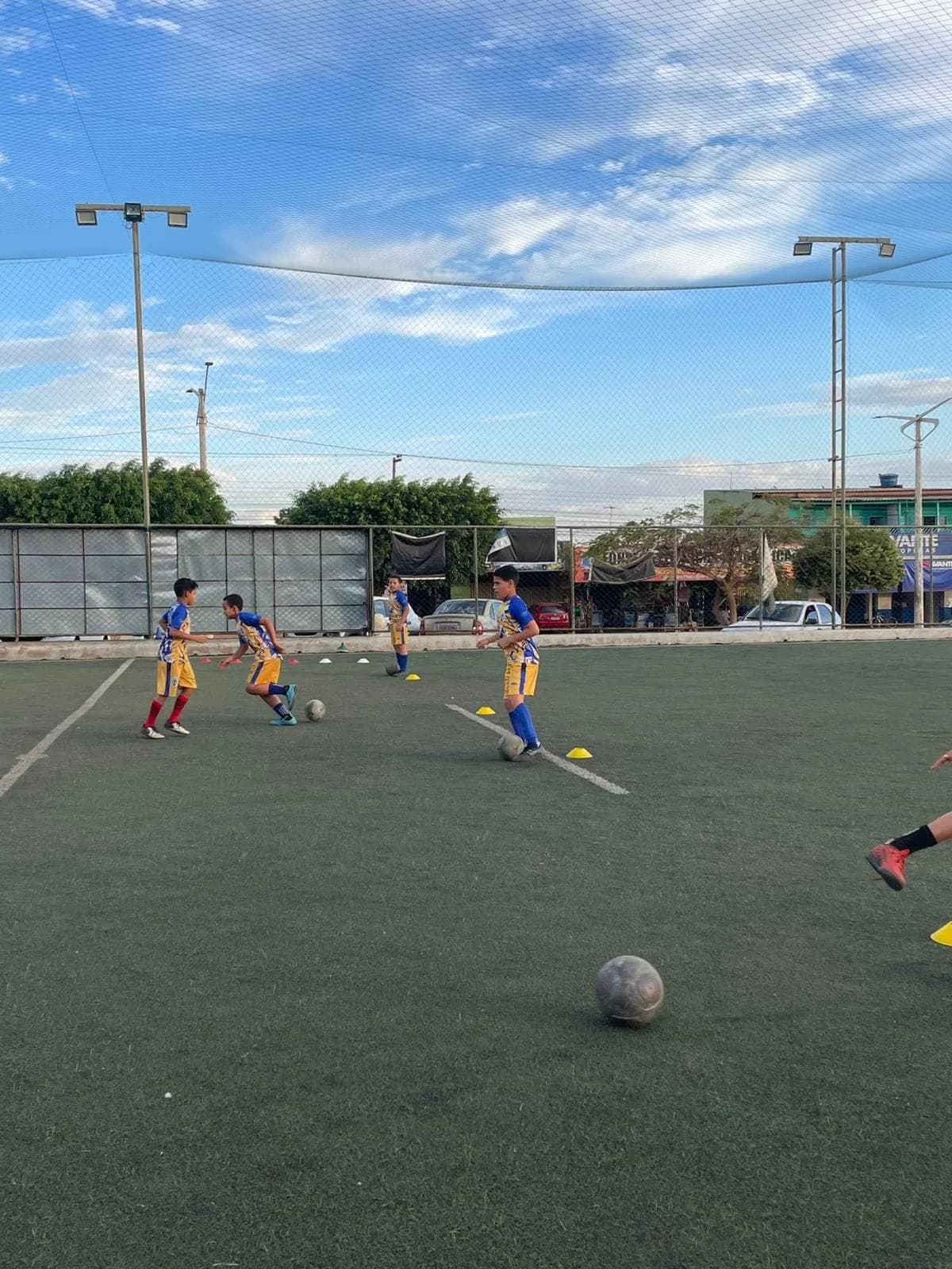 Alunos treinando fundamentos com bolas e cones
