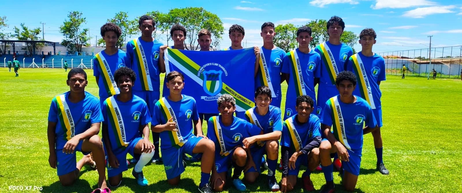 Equipe de azul posando com a bandeira do clube