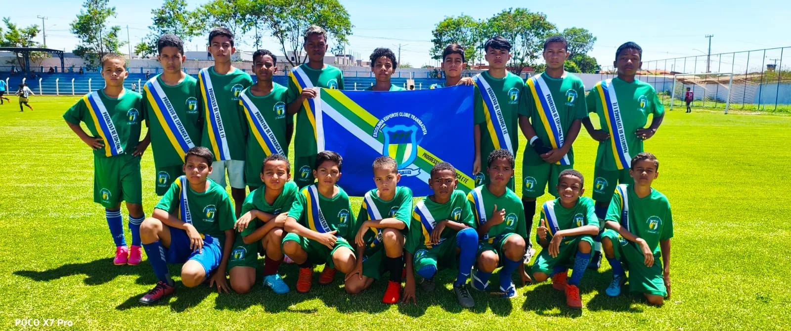 Equipe de verde posando com a bandeira antes do jogo
