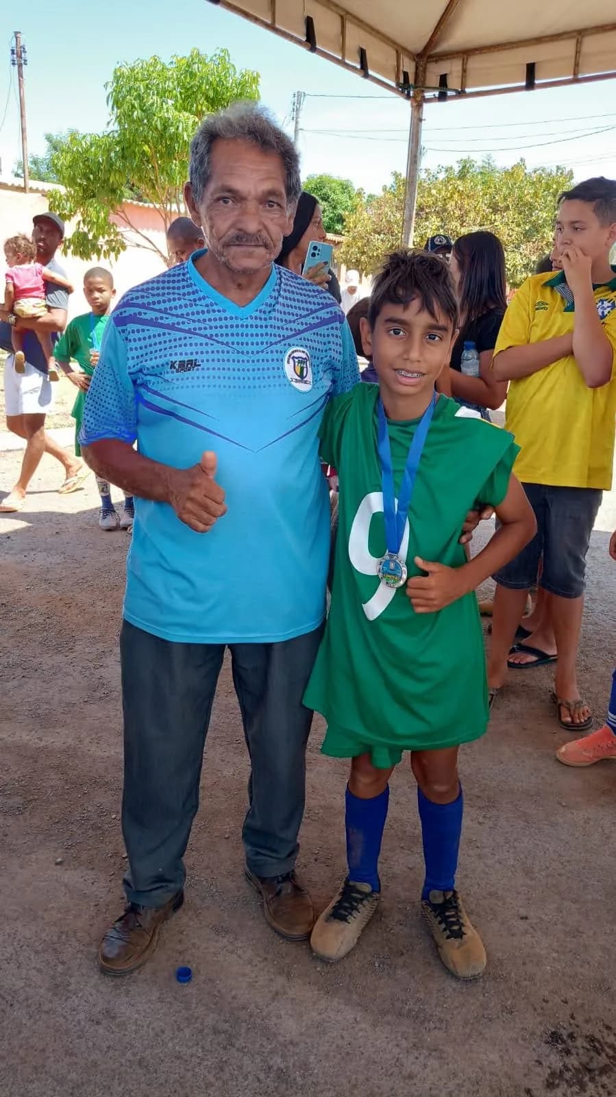 Treinador ao lado de um aluno medalhado após a competição