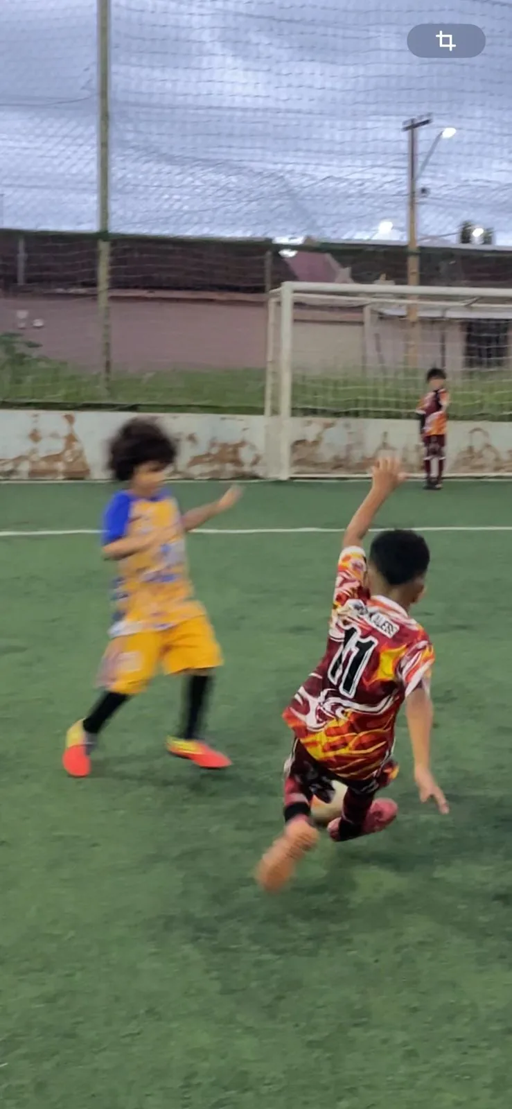 Criança de amarelo chutando a bola durante o jogo