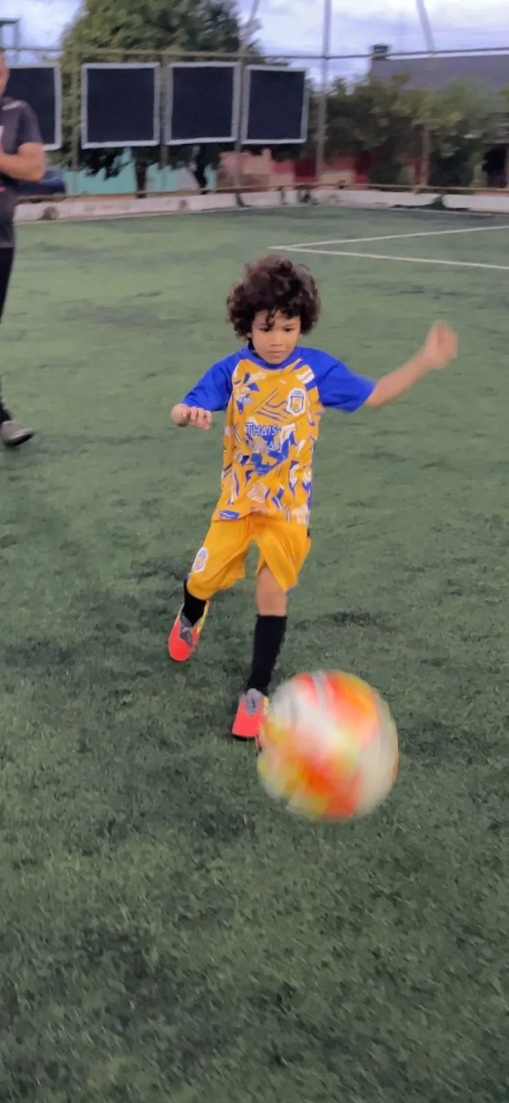 Criança de uniforme amarelo finalizando a gol