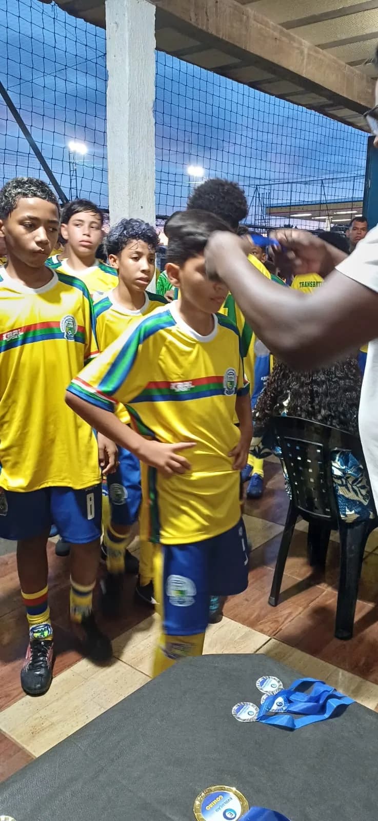 Atletas de amarelo recebendo medalhas na premiação