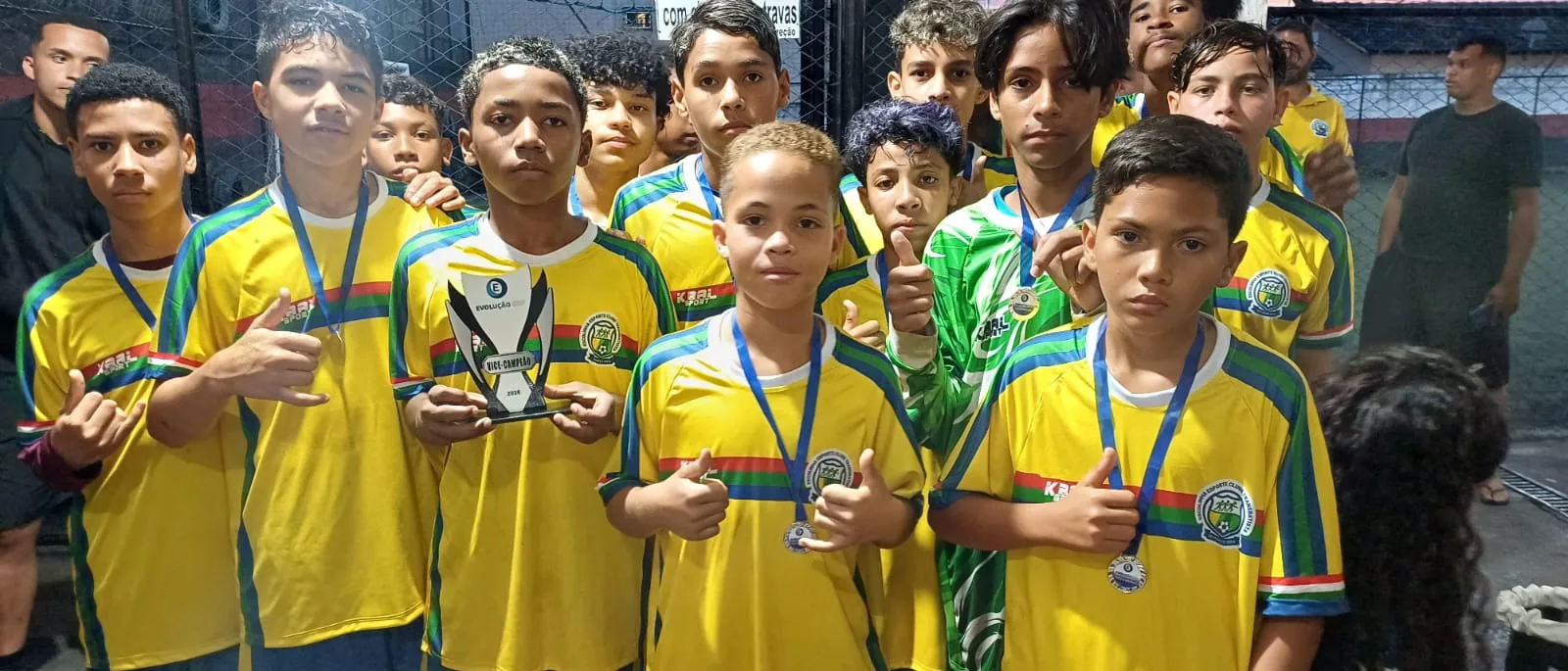 Atletas exibindo medalhas e troféu após a competição