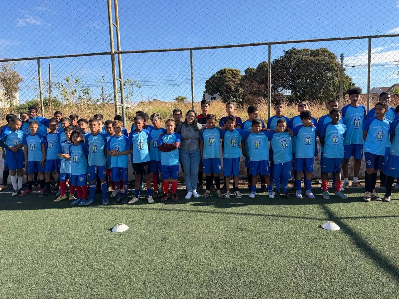 Grande grupo de alunos de azul reunido no campo