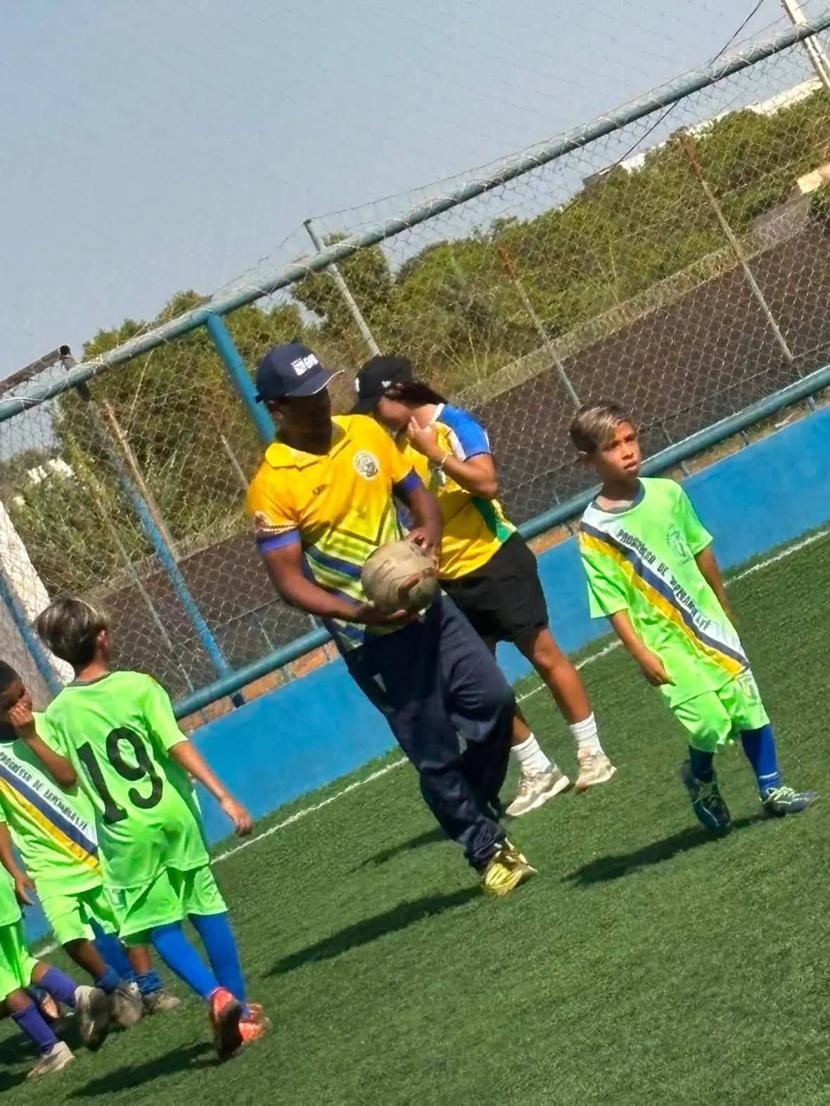 Treinador entregando a bola para os alunos no treino